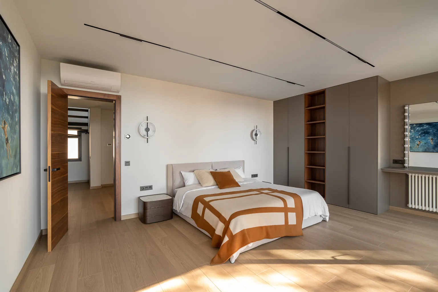 Master bedroom with floor-to-ceiling wardrobes, open shelving, an upholstered headboard, parquet and magnetic lighting tracks