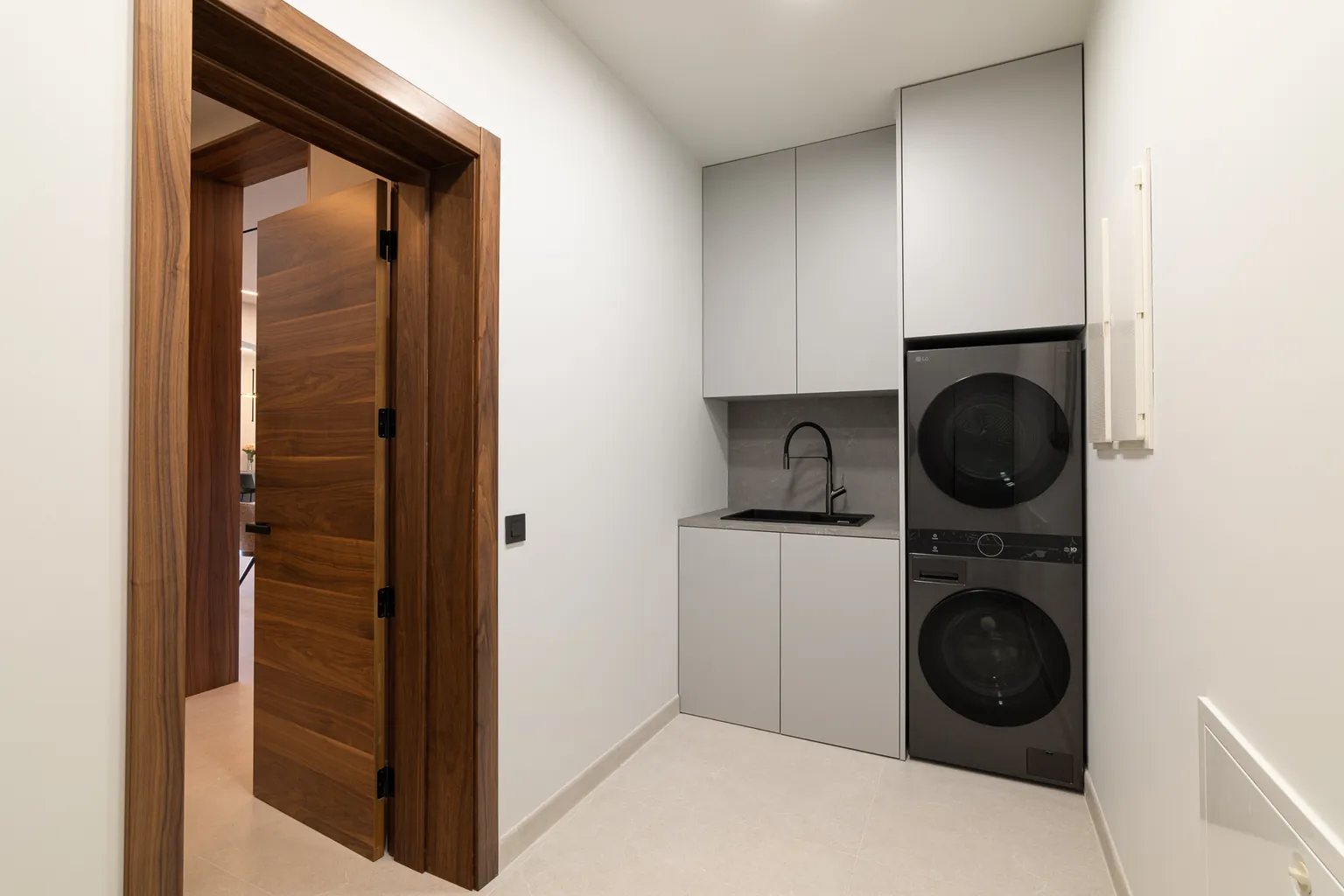 Utility room with bespoke grey cabinets, a sink and a stacked washer and dryer