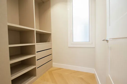 Dressing room with shelves, drawers and a frosted glass window next to a white door