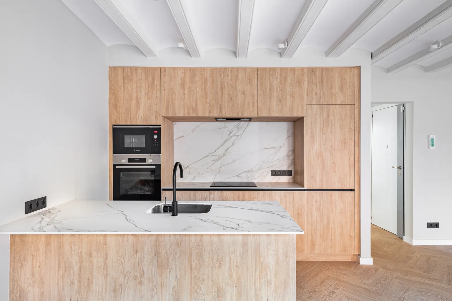 Kitchen with wood-look fronts, marble-effect splashback and worktop, built-in oven and microwave and black tapware