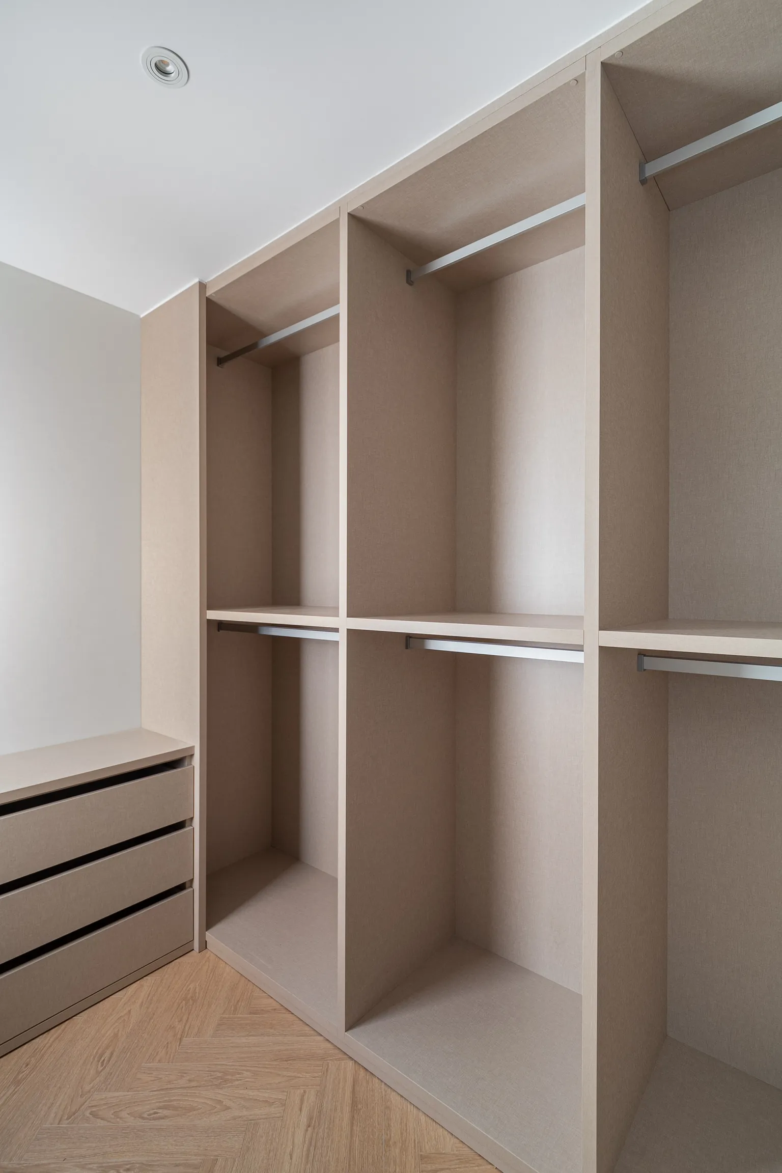 Bespoke dressing room with open modules, hanging rails and a chest of drawers in a light textile finish