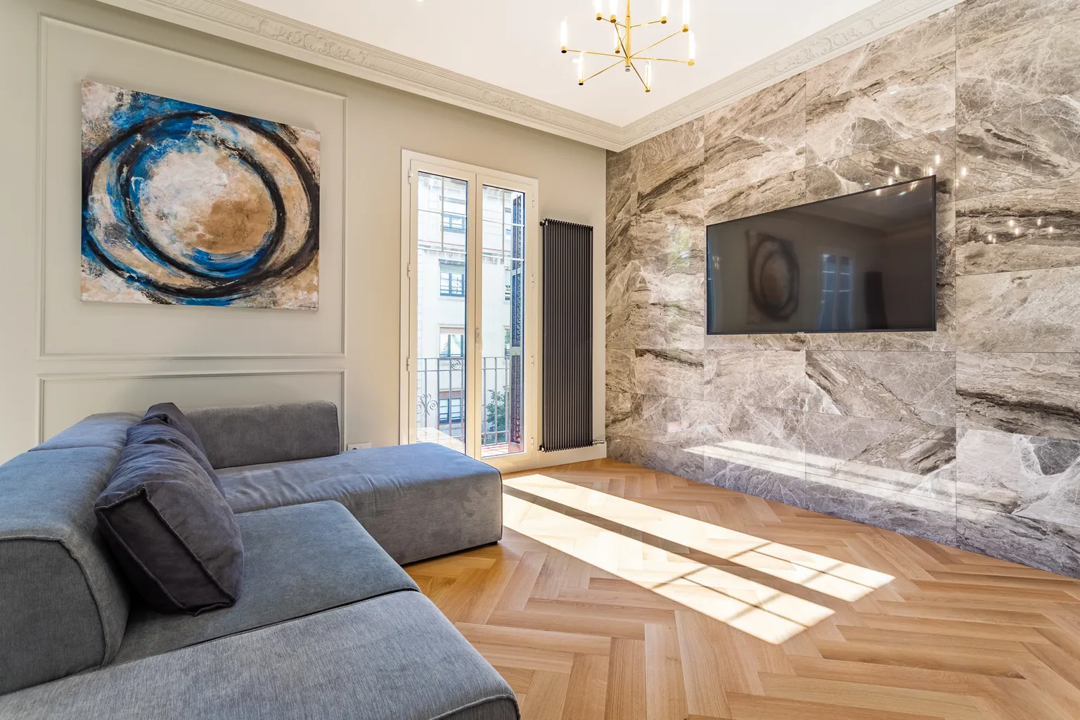 Salon rénové dans un appartement de l'Eixample à Barcelone, avec moulures d'origine restaurées et parquet en bois à bâtons rompus