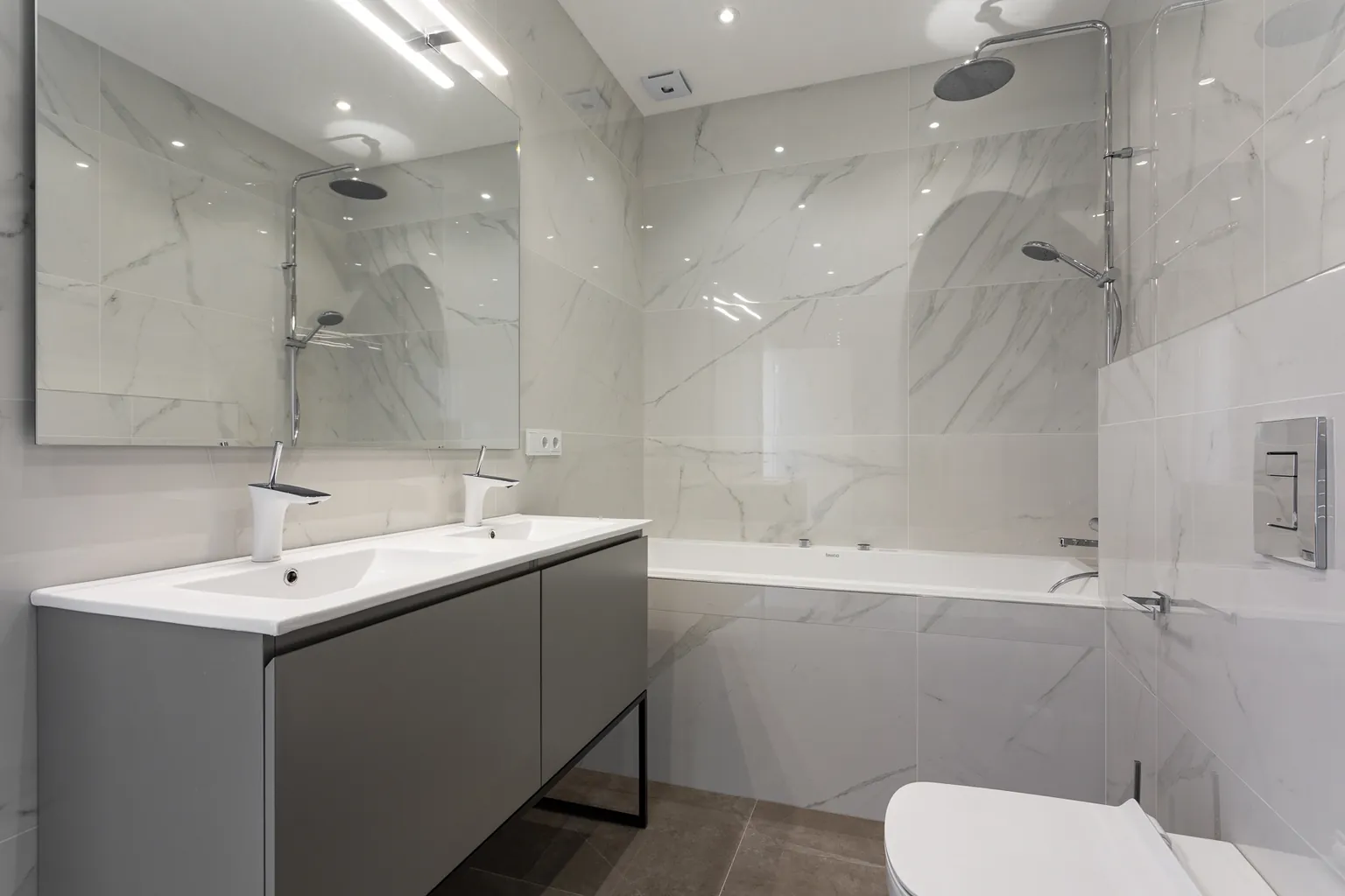 Salle de bain en grès cérame effet marbre, meuble double vasque et baignoire avec douche de pluie